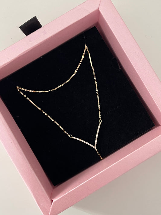 A delicate gold chain necklace displayed on a black velvet insert inside a pink jewelry box.